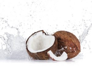 Cracked coconuts with water splash on white background, close-up.